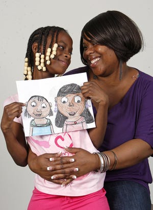 Savion Brown, 8, of Brockton, winner in the 8-year-old category of the 2011 Draw Your Mom contest, holds her winning drawing as she sits with her mother Kenya Brown in Brockton on Tuesday, May 3, 2011.