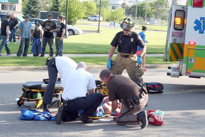 Emergency personnel attend to victim of bicycle-car accident on Main Street in Ionia Monday.