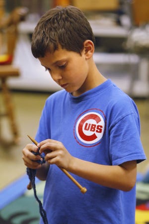 Gavin Hill, 8, works on his knitting, during an after school knitting class. (Paul Tople/Akron Beacon Journal)