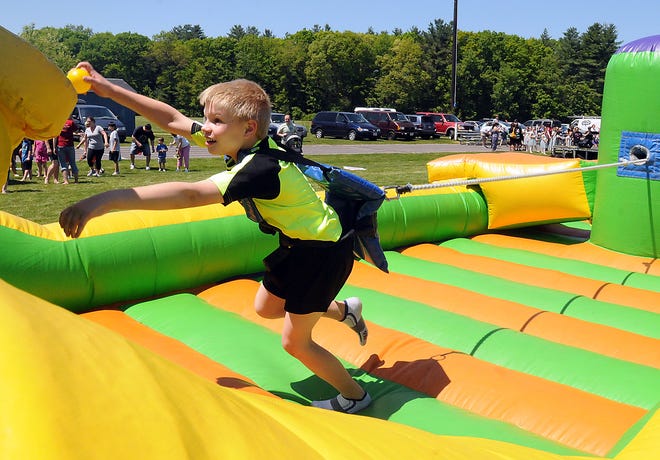 Sean Murphy, 8, stretches to dunk a ball in a bungee cord game during Medway Pride Day, Saturday in Medway.