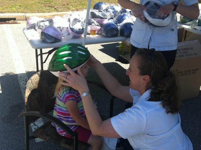 Patricia Gaines, 7, of Norwich, gets fitted for a bicycle helmet by UConn Avery Point nursing student Amanda Osmanski during The William W. Backus Hospital’s seventh annual Summer Safety Camp on Saturday.