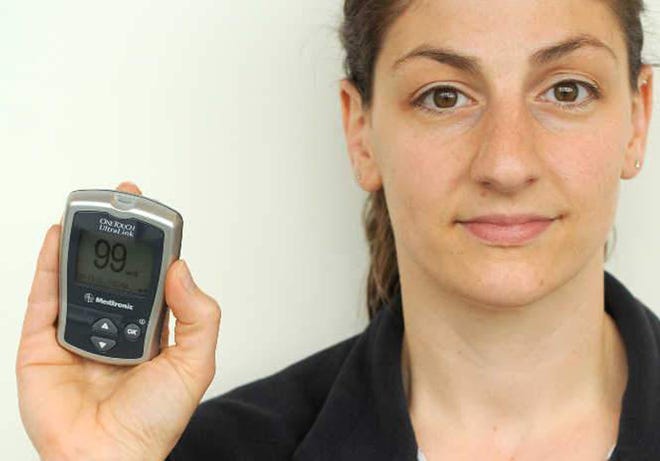 Melissa P. Morin, a patient care associate II in the diabetes department at UMass Memorial Health Care, has type 1 diabetes. She is holding a blood glucose meter that synchs with a computer program that displays the data.