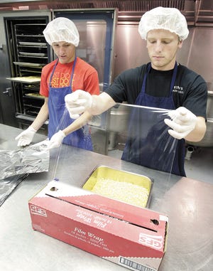Perry high seniors involved in the recent food fight at the school, Nick Williams (left) and Stanley Spangler, package corn while volunteering at the Meals on Wheels of Stark and Wayne Counties.