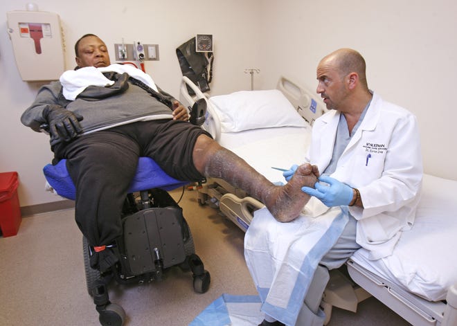 Dr. Steven D. Gross, a podiatrist, treats patient Steven Sullivan at Aultman Hospital Thursday. Sullivan had his right leg amputated and when he put weight on his new prosthesis, he broke his left leg. The recovery process has been long for Sullivan.