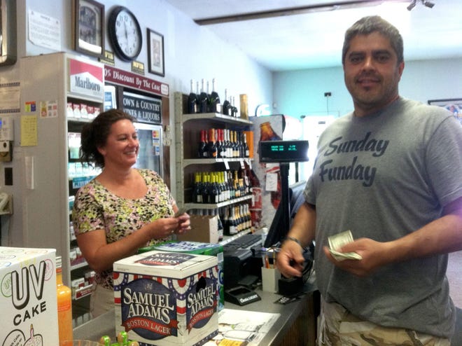 Michelle Daleb rings up Roberto Rodrigues on Sunday at Town and Country Wine and Liquor in South Windham.