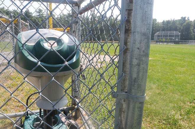 A Mosquito Magnet sits fenced in near the baseball fields baseball fields behind the Merrill Elementary school in Raynham.