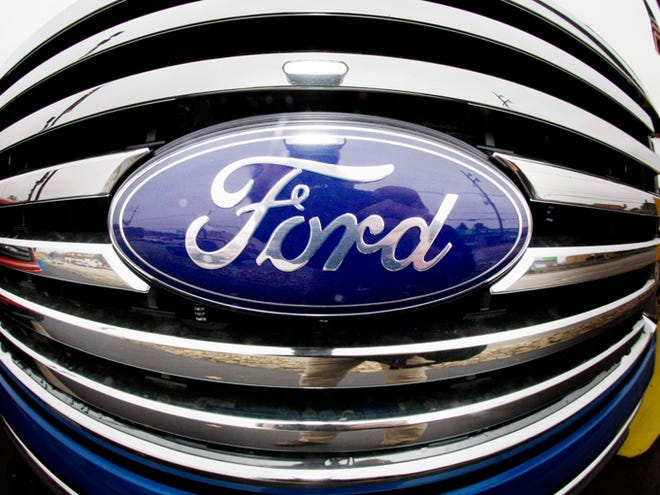 In this Oct. 29, 200,9 file photo made with a fisheye lens, the Ford Blue Oval logo is shown on the grill of a pickup truck on a Ford dealership in Wexford, Pa. Moody's Investors Service raised Ford's debt ratings to investment-grade Tuesday for the first time in seven years.