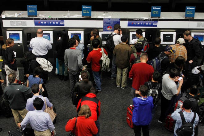 In this June 17 file photo, passengers crowd the kiosks to check in and print boarding passes at San Francisco International Airport in San Francisco. Airlines are setting aside more rows for passengers willing to pay extra for a better seat. That means families are going to struggle to sit next to each other unless they booked early or are willing to shell out anywhere from $5 to $180 extra, each way.