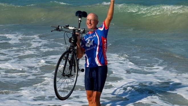 The Rev. Scott Alexander, minister at Unitarian Universalist Fellowship of Vero Beach, pumps his fist after dipping his bicycle in the ocean in front of Waldo's Driftwood Resort on Tuesday afternoon. Alexander biked 3,300 miles and raised more than $50,000 to benefit the Harvest Food and Outreach Center, as well as the international organization Stop Hunger Now.