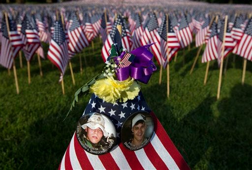 Buttons featuring the likeness of fallen U.S. Marine Lance Cpl. Alexander S. Arredondo, left, and his brother Brian Luis Arredondo, right, who took his own life following the death of Alexander, are attached to an American flag in front of thousands of flags planted in the Boston Common, in Boston, Wednesday, May 23, 2012. Relatives and volunteers planted the 33,000 flags in the historic park in advance of the Memorial Day weekend, in tribute to Massachusetts soldiers killed in conflicts as far back as the Civil War. Alexander was killed in 2004 in Iraq. (AP Photo/Steven Senne)