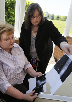 Steven Hudson's mother Donnie Hudson (left) and her daughter Jaime Hudson look at copies of xrays of Steven's broken bones. Hudson was severely injured in February when a car carrying two men slammed into his car, killing them both and leaving Hudson with a long recovery. (Paul Tople/Akron Beacon Journal)