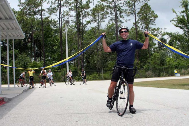 Photos by Maggie.FitzRoy@jacksonville.com Ponte Vedra High School teacher Jeff Nethery celebrates putting 10,000 miles on his bicycle last week as he crosses a "finish line" placed at the school by his students.
