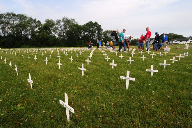 Volunteers place 6,437 crosses in a field behind Immanuel Lutheran Church in Freeport Saturday. The crosses, each with a name, represent service men and women killed in Afghanistan and Iraq from 2001 to present.