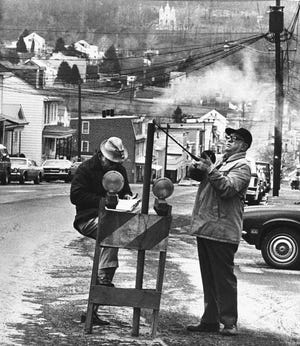 In this April 1981 file photo, U.S. Bureau of Mines' John Stockalis, right, and Dan Lewis drop a thermometer through a hole on Main Street in Centralia, Pa., to measure the heat from a shaft mine blaze that still burns under the town.