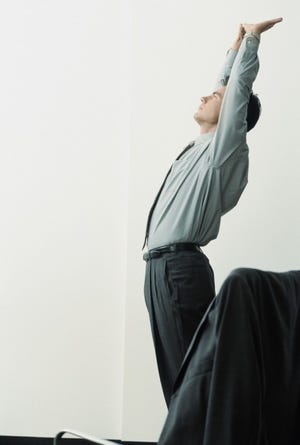 Businessman Stretching at Work --- Image by © Royalty-Free/Corbis