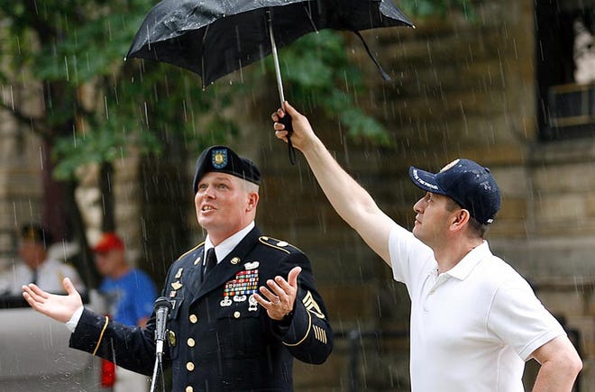 Army Master Sgt. Jack Harlan Jr. of Knoxville gestures to the sky as Galesburg Mayor Sal Garza holds an umbrella over him to keep him dry during remarks at a remembrance ceremony at the Knox County Courthouse on Monday morning. The event followed the annual downtown Memorial Day Parade.