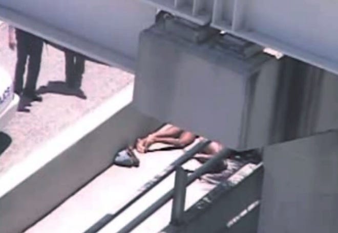 In this image taken from video, Miami police officers stand watch near a naked man, second from right, who was shot dead by a police officer when he refused to stop chewing on the face of the naked man next to him, partially obscured by a railing, on the MacArthur Causeway ramp onto Northeast 13th Street in Miami, Saturday, May 26, 2012. The victim was taken to a nearby hospital. Police say neither man's identity is known.