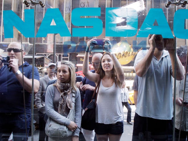 Curious bystanders watch through the Nasdaq windows as Facebook shares begin trading Friday in New York. Facebook's stock has fallen below $30 for the first time since its much-awaited public debut this month.