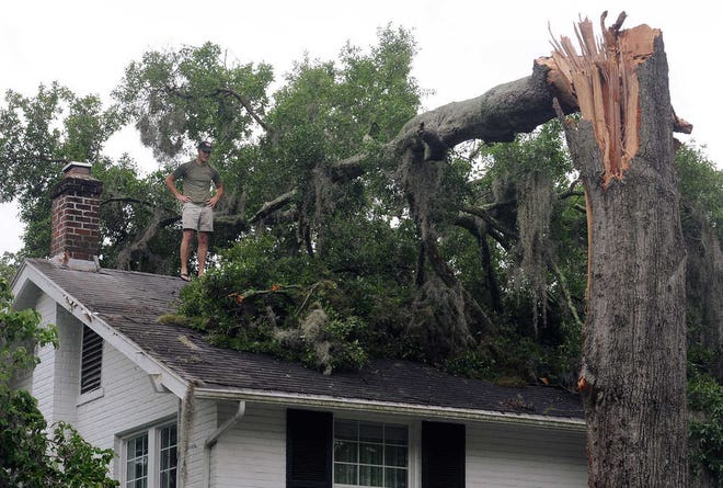 Wes Akers inspects damage on a home Monday in Avondale, Fla., caused by a downed tree in the aftermath of Tropical Storm Beryl. Beryl came ashore early Monday near Jacksonville Beach with near-hurricane-strength winds of 70 mph.
