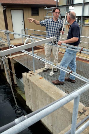 Rockford College professor Troy Skwor (left) talks to Warren Adam of the Rock River Water Reclamation District above the outlet for treated water Friday, May 25, 2012, at the plant in Rockford.