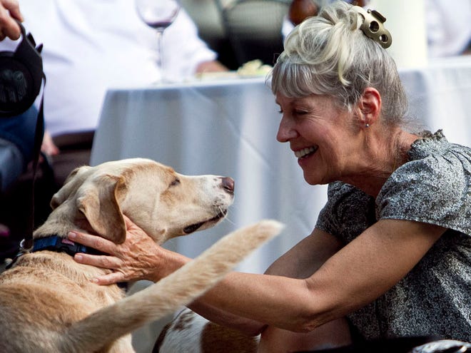 In this May 8, 2012 photo, Marcia Mathis greets "Atticus" at the Pooches on the Porch event to benefit the SPCA at Kitchen on George restaurant in Mobile, Ala. Restaurants around the country are offering doggie adoption happy hours and dinners to raise money for animal shelters. (AP)