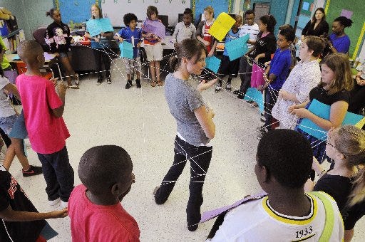 Teacher Jenny Studenski leads her fifth-grade students at Hyde Park Elementary School through an exercise where they use string to make physical connections between the students to help them learn about the connections between the creatures of the rainforest.