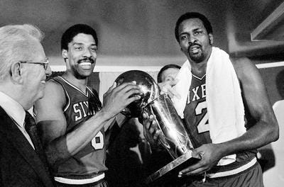 In this Tuesday, May 31, 1983 file photo, Philadelphia 76ers Julius Erving, left, and Moses Malone, right, hold the NBA Championship trophy after defeating the Los Angeles Lakers in Los Angeles. Twenty five years and nearly 100 seasons have passed since fans last crowded Philadelphia's sidewalks to celebrate a professional sports championship. (AP Photo/File)