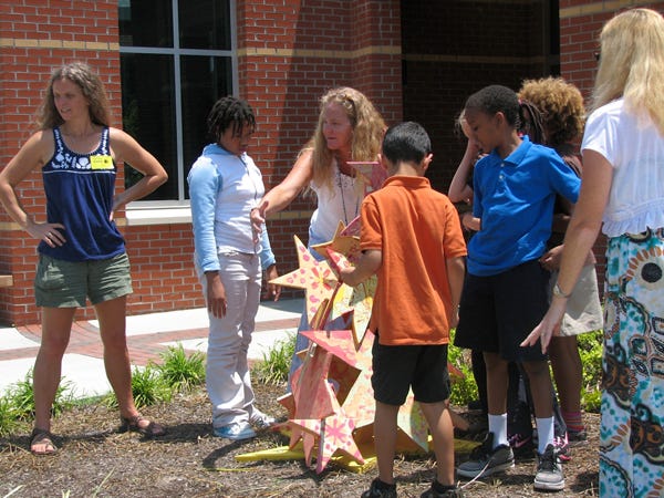 UNCW art professor, Andi Steele (left) and Snipes Elementary art teacher, Melony Connor, talk to students about what they've learned from building their latest art sculpture. Photo by:Corey Strickland