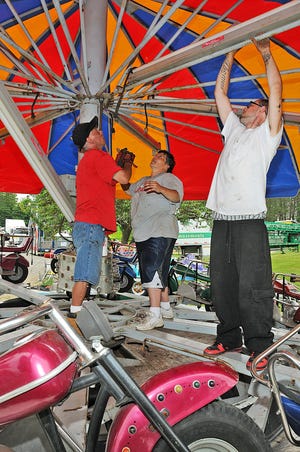 From left, Mike Pasaska, Margaret LePage and Thomas Brabant, all of Fall River, help set up one of the rides in preparation for the Dighton Cow Chip Festival this weekend.