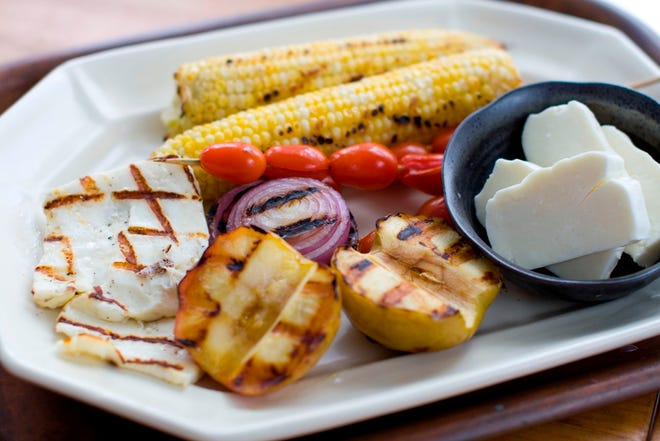 A recipe using Halloumi in a salad combined with grilled corn, apples and onions on a platter. (The Associated Press)