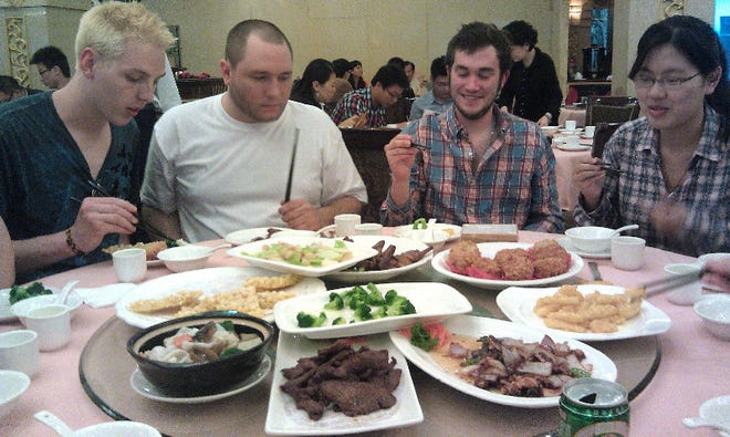 In China, meals are shared by relying on a glass carousel in the middle of the table spun by diners. Here ESU students Dan Rue, Andrew Spina and Casey Munsheno and Zhu Xuejin, a Chinese student, feast from different plates.