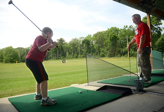 Steven Ritacco Sr. of Medway watches his son Steven Jr., 9, take a swing at Cassidy's Clubhouse driving range in Medway yesterday.