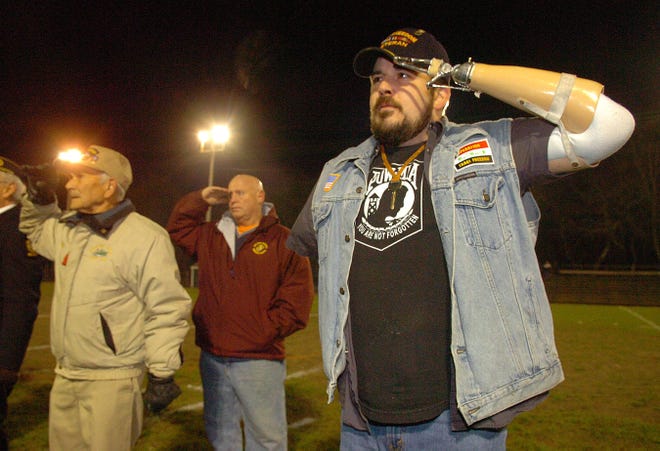 Disabled veteran Peter Damon salutes during the national anthem before a recent Middleboro High School football game. Veterans Francis Morrison and Walter Campbell also were honored at the game.