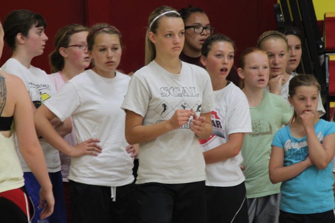 A group of girls listens to instructions for a basketball drill.?