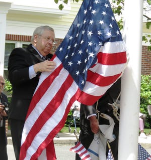 State Sen. Richard Moore raises the flag at Atria Draper Place in Hopedale during Thursday's Flag Day events.