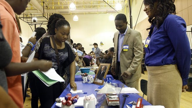 Job seekers stop by the Walmart recruiting table this week during a job fair for young adults at John F. Kennedy Middle School sponsored by the office of the Mayor of Riviera Beach. Hundreds of applicants ages 17-25 turned out for a shot at a summer job. Manning the table, Aisha Shefton, right, and store manager Jason McMurry.