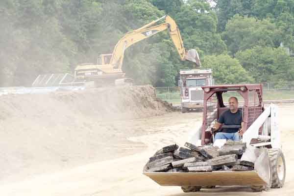 Photo by Bruce A. Scruton/New Jersey Herald - A small front-end loader hauls away a load of broken asphalt while, through the dust, a bigger shovel loads a dump truck in the middle of the Newton High School track.