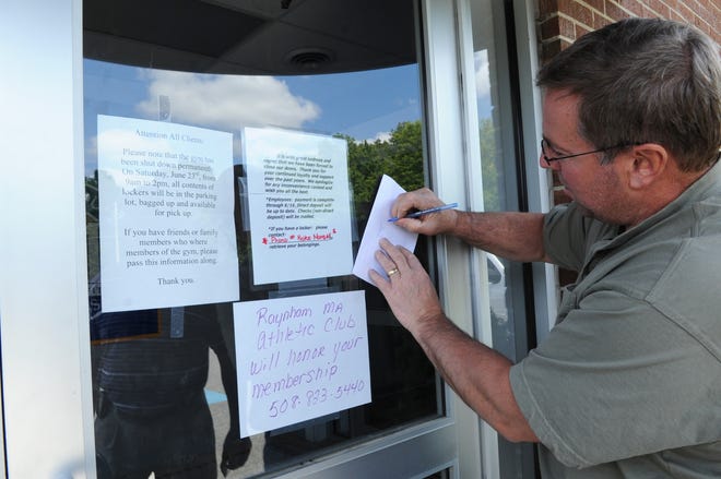 Gary Twombly of Newburyport writes down information left on the front door during a visit to the Metro South Athletic Club in Brockton on June 18, 2012. The club stunned members by abruptly closing.