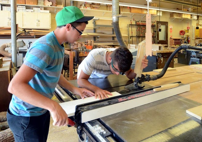 Matt Haag, 19, (left) helps 
 Aaron Lodato , 19, both of Evesham, align a piece of plastic before cutting it for a project during the woodworking camp.