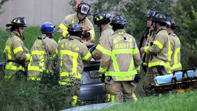 After removing the roof from her Ford Focus, West Palm Beach firefighters remove the driver of the car which ran off I-95 north of Palm Beach Lakes boulevard Tuesday.