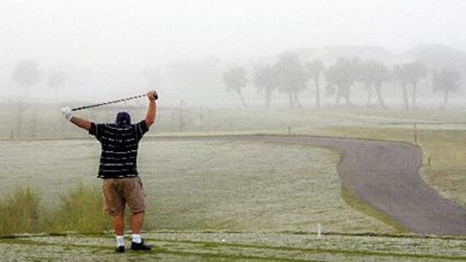 A golfer loosens up before teeing off in the early morning fog at the Abacoa Golf Club.