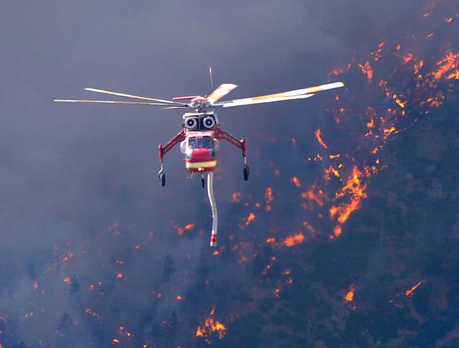 A helicopter returns to Glen Eyrie Reservoir in Colorado on Tuesday to refill water tanks to fight the Waldo Canyon fire. The fire spread to the north as afternoon winds spread embers into the air.