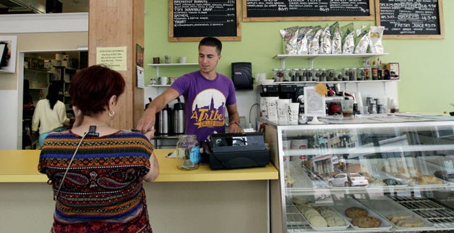 Alex Butters gives a patron her change at the Green Bean coffee shop in New Bedford on Tuesday.