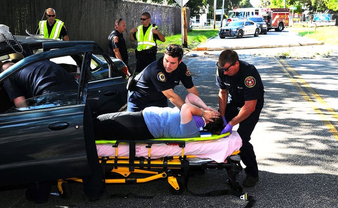 St. Johns County Fire Rescue firfighter/paramedics Matthew Sara and Michael Silverstein help a woman who crashed her car into a telephone pole on Masters Drive in St. Augustine Thursday morning.