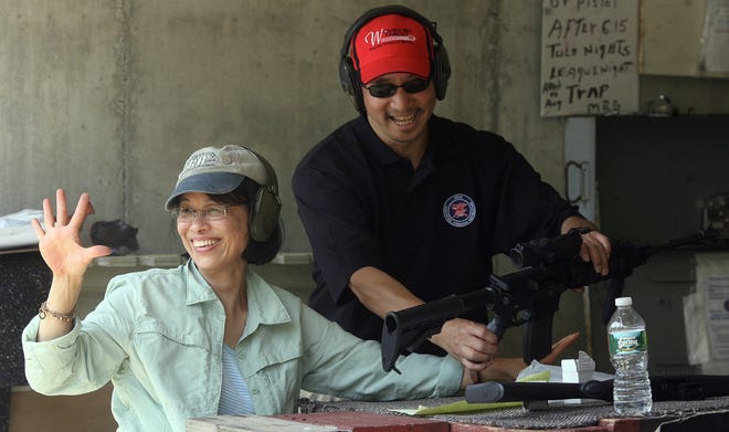 As instructor Kenyon Chin secures the AR 15 rifle, Vera Lee-Chin of Sudbury signals to her friends that she got 5 out of 5 shots in the target. The Gun Owners Action League, with the Maynard Rod & Gun Club sponsored a clinic called Women on Target. The women shot at three different stations using different firearms. Staff Photo by Ann Ringwood
