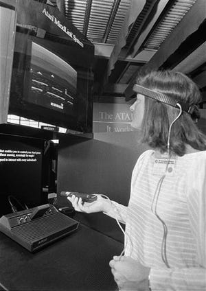 In this June 5, 1984, file photo, a woman in Chicago demonstrates Atari's new game, Mind Link, which utilizes a headband that picks up electrical impulse from the movement of the forehead and transmits them to a receiver attached to a video game or home computer console. (AP Photo/Charlie Knoblock)