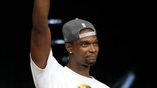 Miami Heat's Chris Bosh acknowledges fans Monday, June 25, 2012, during a rally for the NBA basketball champions in Miami. Hundred of thousands of people filled the streets of Miami for the Heat championship parade, and then 15,000 more got into the arena afterward for a long, loud reception for the NBA's new kings. (AP Photo/Alan Diaz)