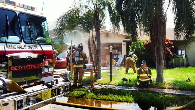 Fire rescue crews work to put out a house fire in the 4300 block of Wilkinson Drive in suburban Lake Worth.
