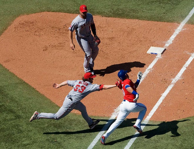 Angels pitcher C.J. Wilson, left, tags out Toronto's Jose Bautista near first base during their game on Sunday - Canada Day - in Toronto. The Angels won, 10-6.
