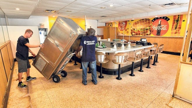 Eric Kieffer, left, helps Jean Celestin, both from White Lion Worldwide Van Lines Inc., remove a refrigerator unit from Hamburger Heaven Friday after the iconic eatery closed.